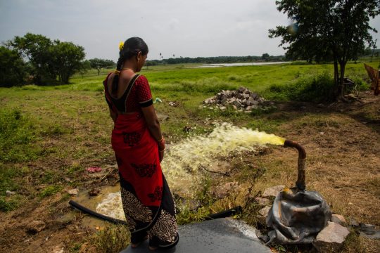 woman standing next to pipe that's spreading  contaminated water